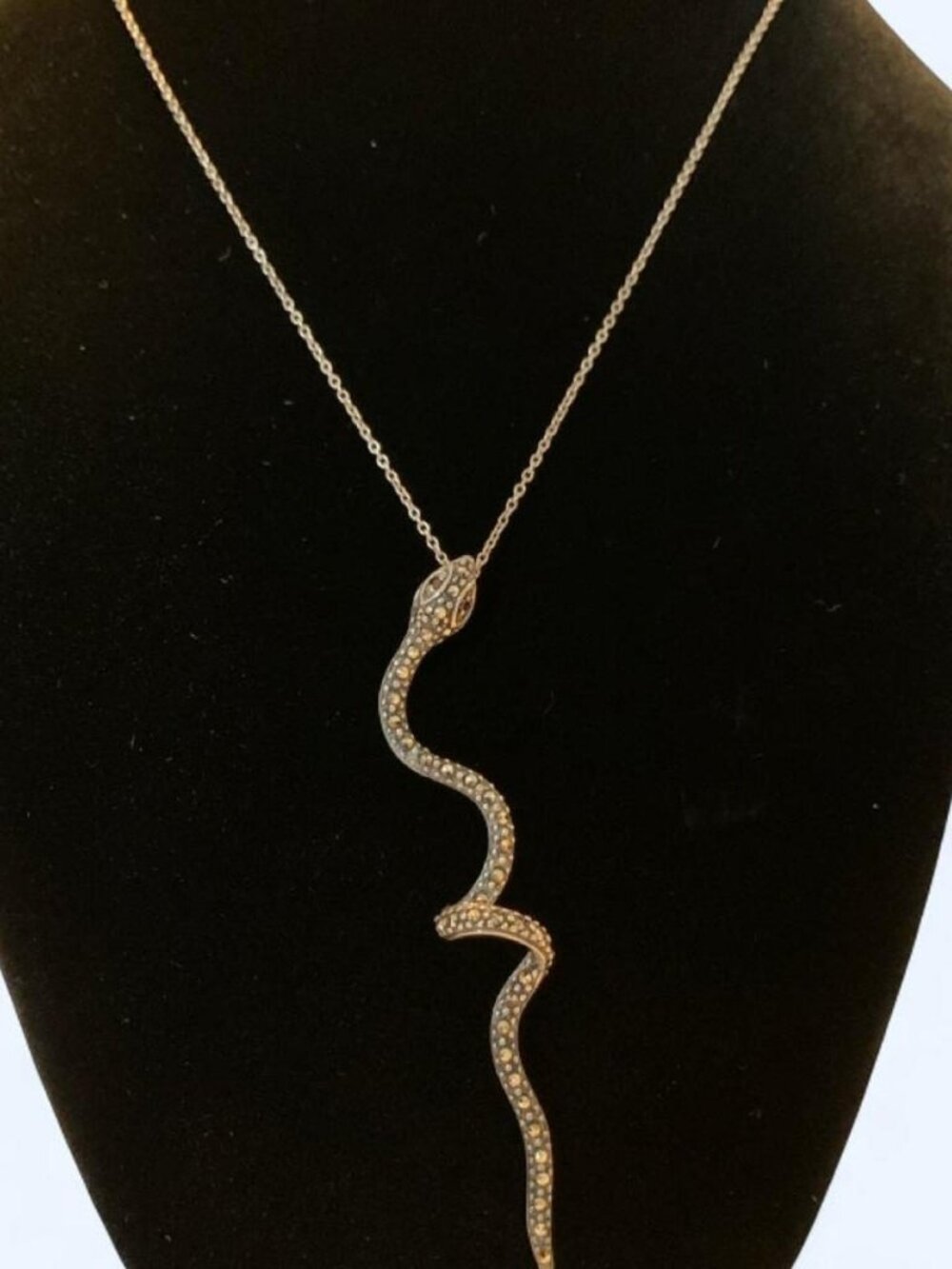 An elegant, elongated snake pendant necklace featuring a sinuous S-curve body de